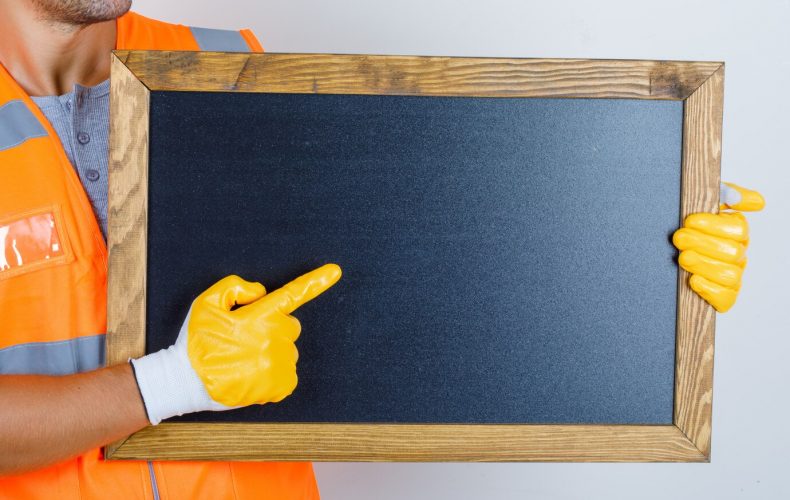 male-builder-uniform-gloves-showing-something-blackboard-front-view_176474-10025